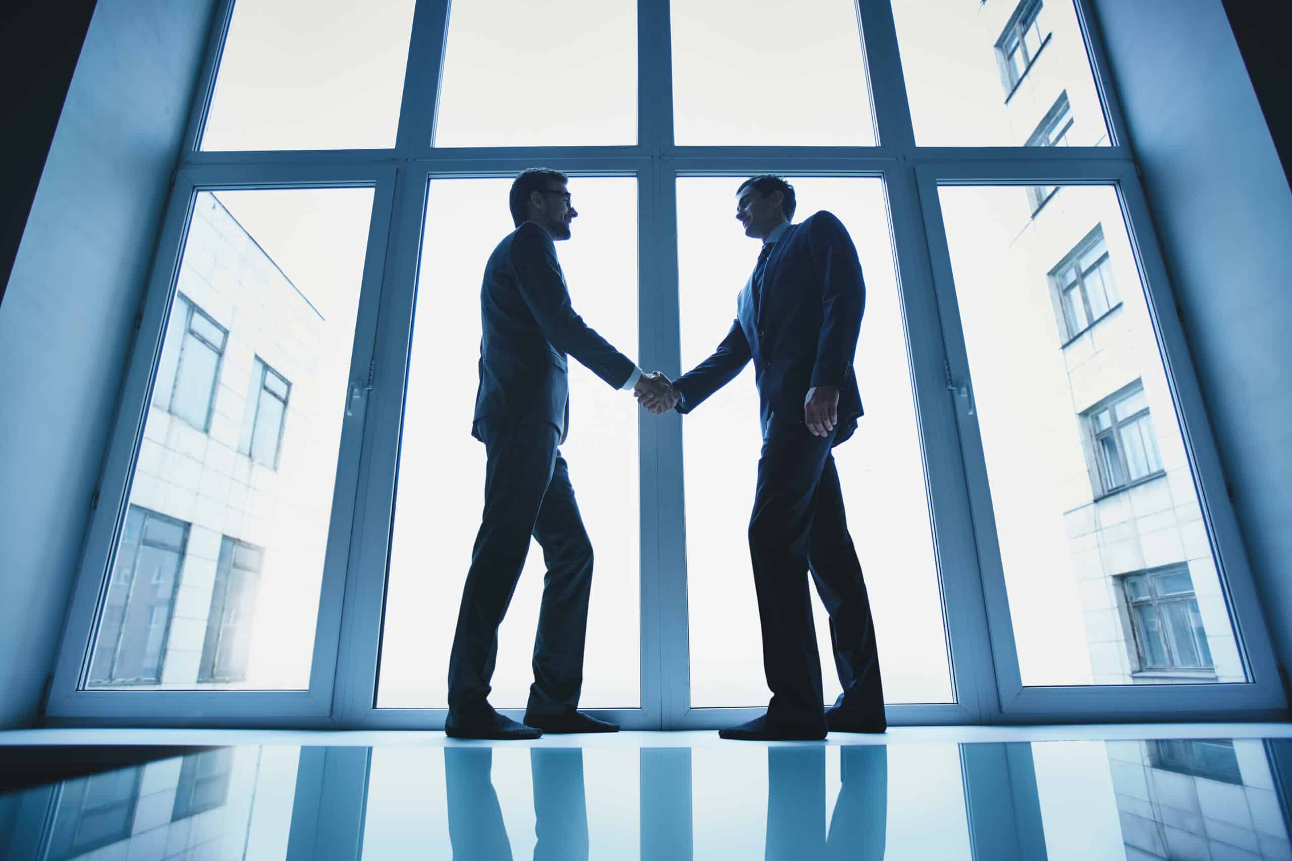 A handshake between two professionals in suits, representing expert business support services.
